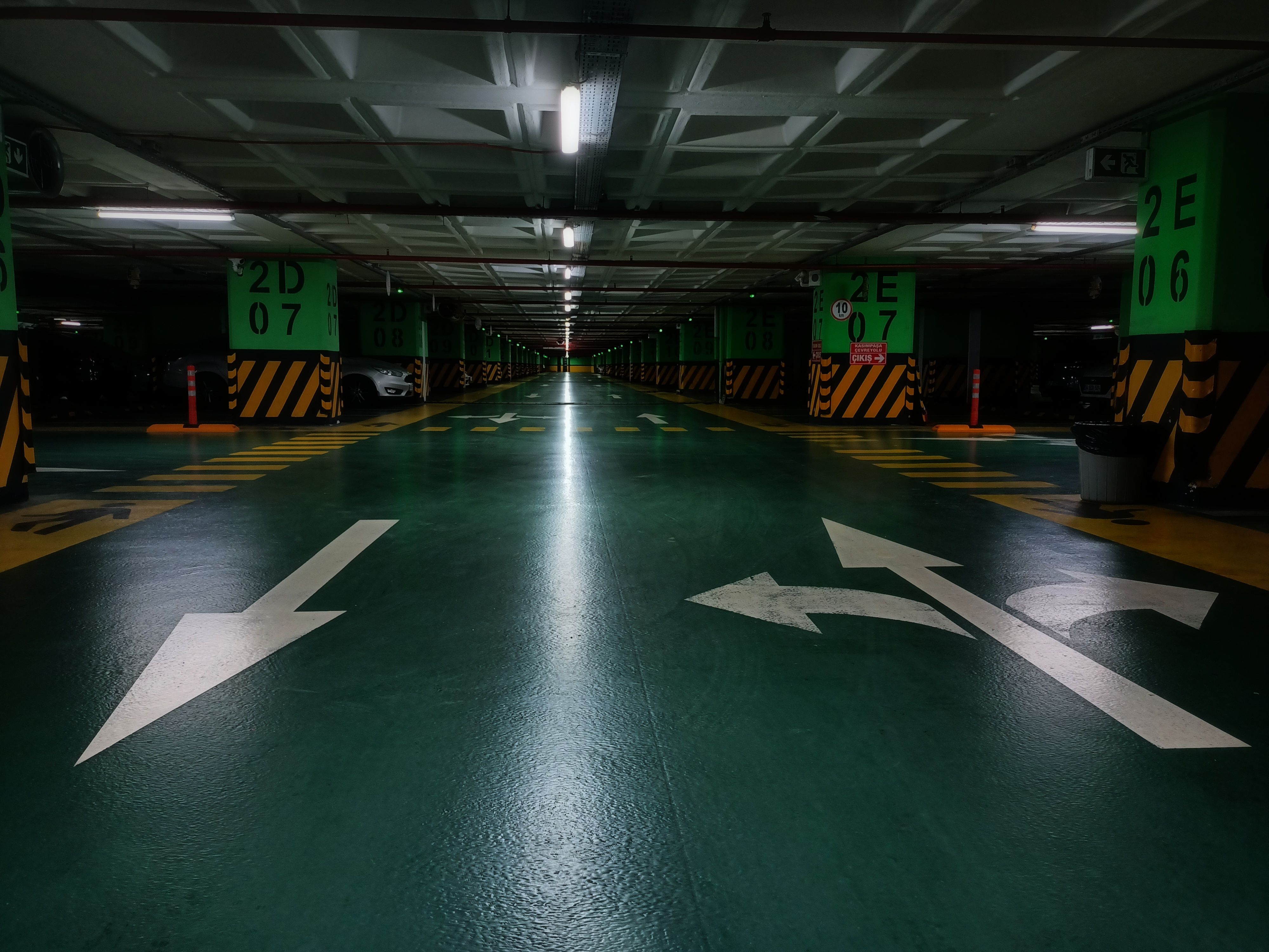 Green polyurea-coated parking deck with white directional arrows