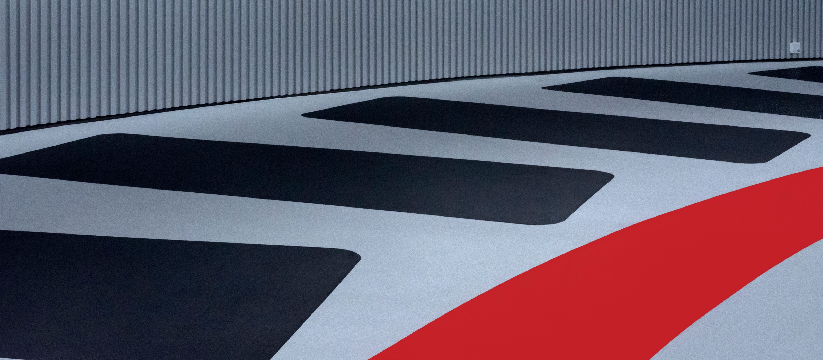 Polyurea-coated parking deck with black parking bays and a sweeping red lane marking