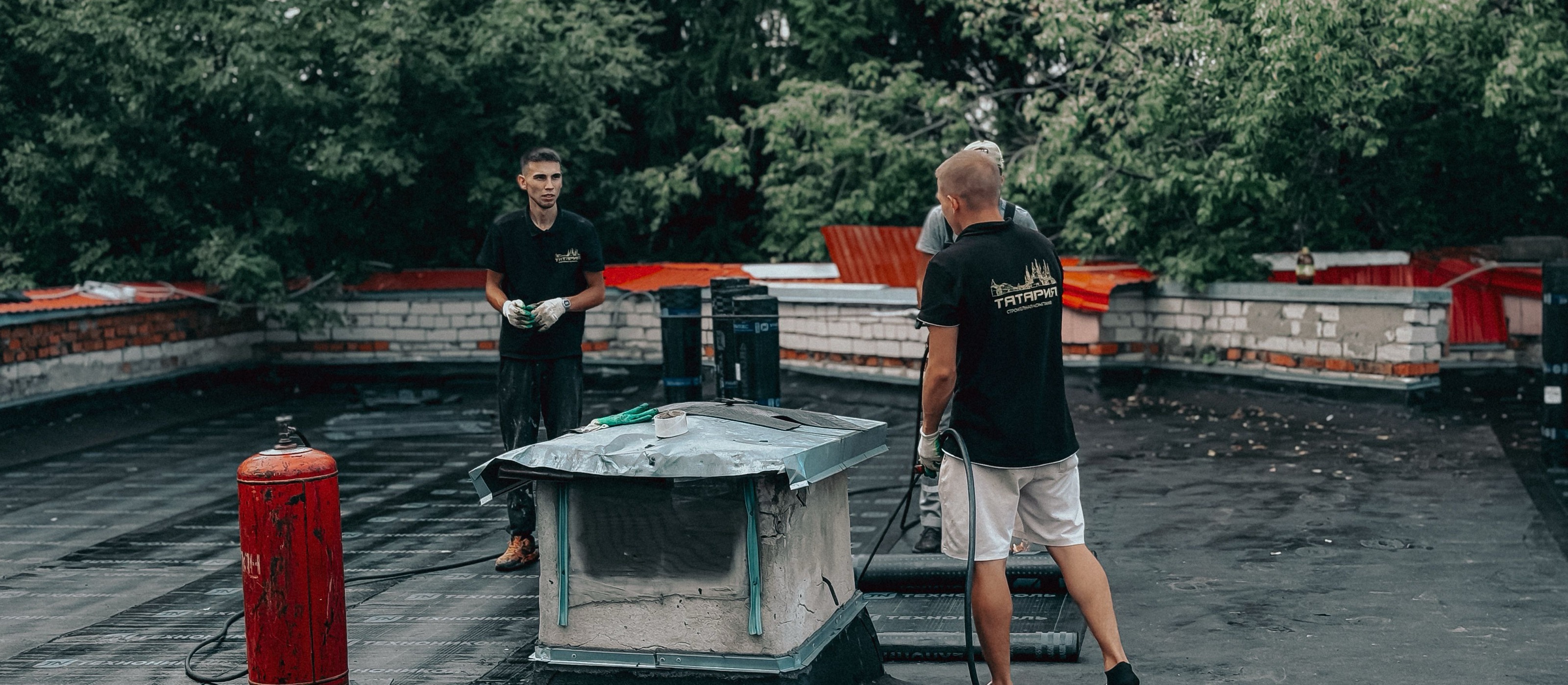 Waterproofing crew at work on a flat roof, applying the protective membrane system