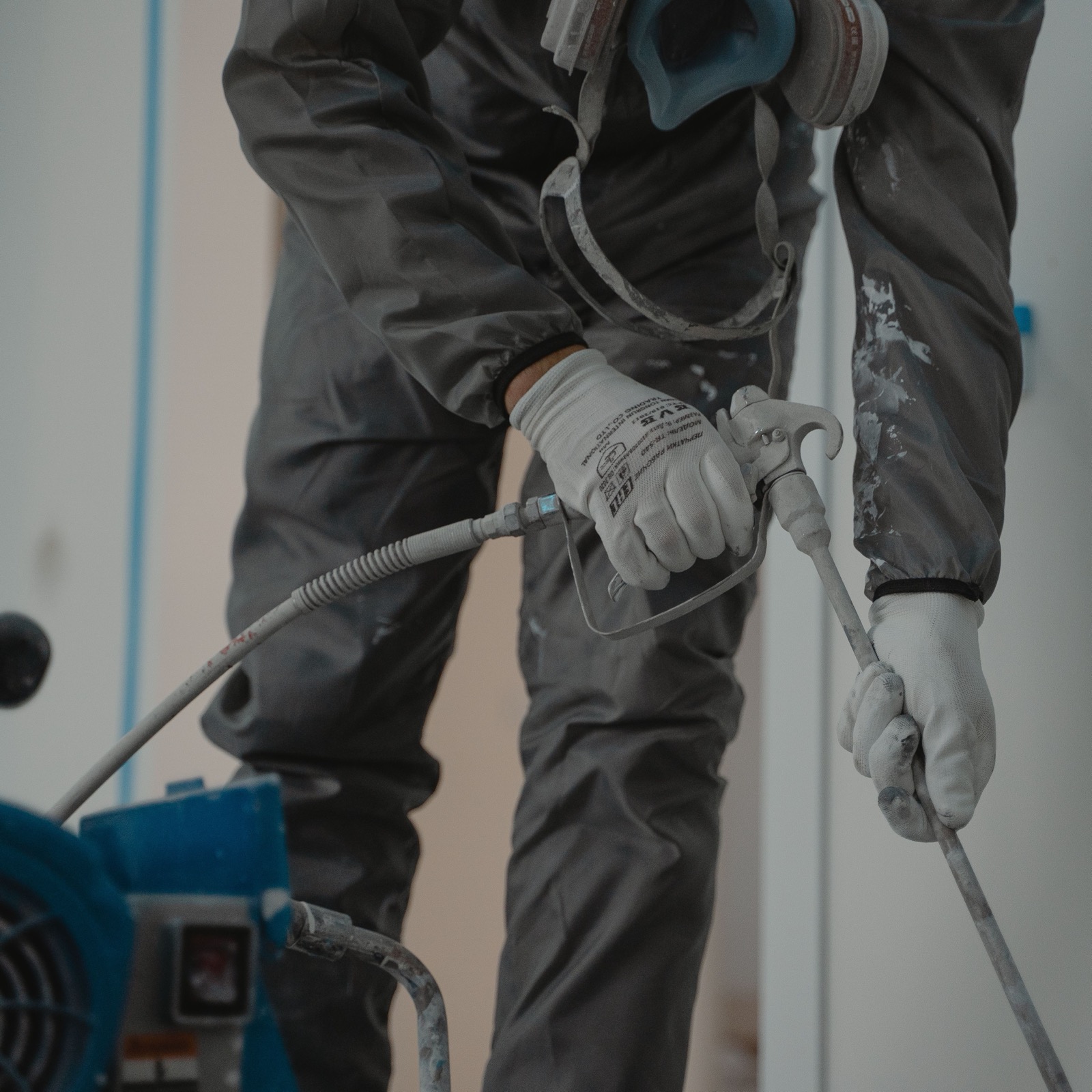 Operator in respirator working with an airless spray machine and gun